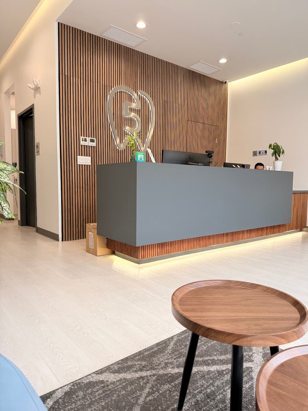 Five Dental's reception desk in front of a slatted wood wall with the practice's tooth logo
